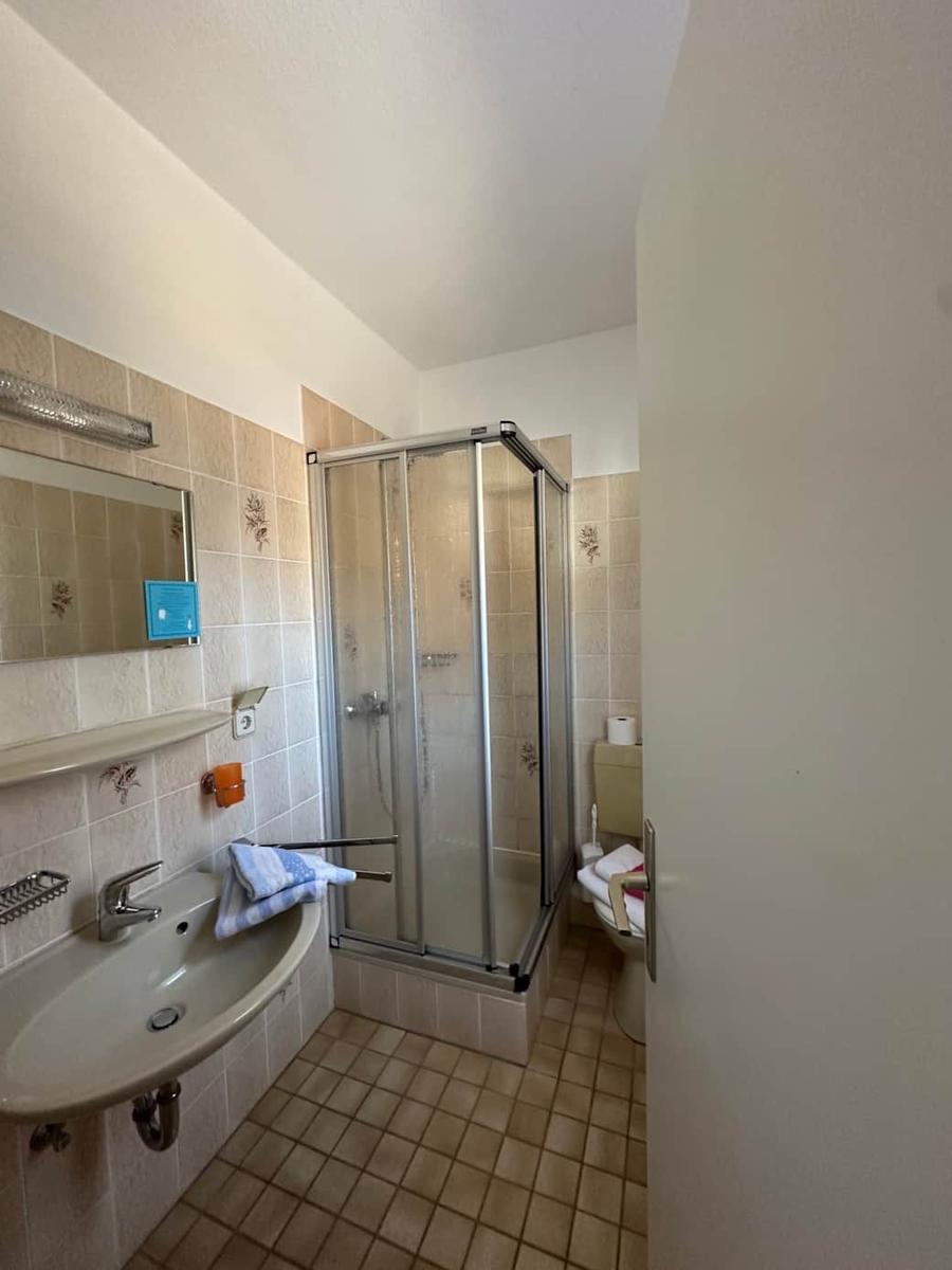 Badezimmer mit Dusche, Waschbecken und Toilette.