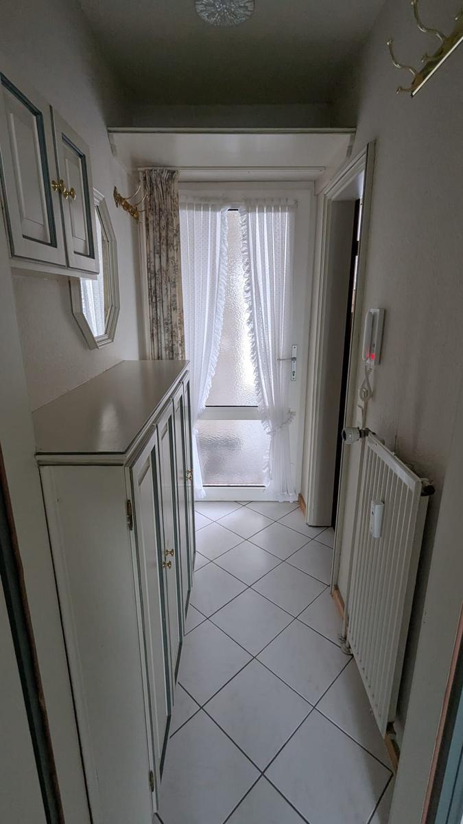 Flur mit Garderobe, Heizkörper und Tür zum Außenbereich.