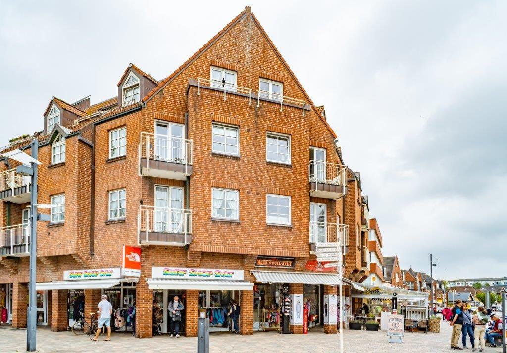 Zweistöckiges Gebäude mit Geschäften im Erdgeschoss und Balkonen an den Fenstern.