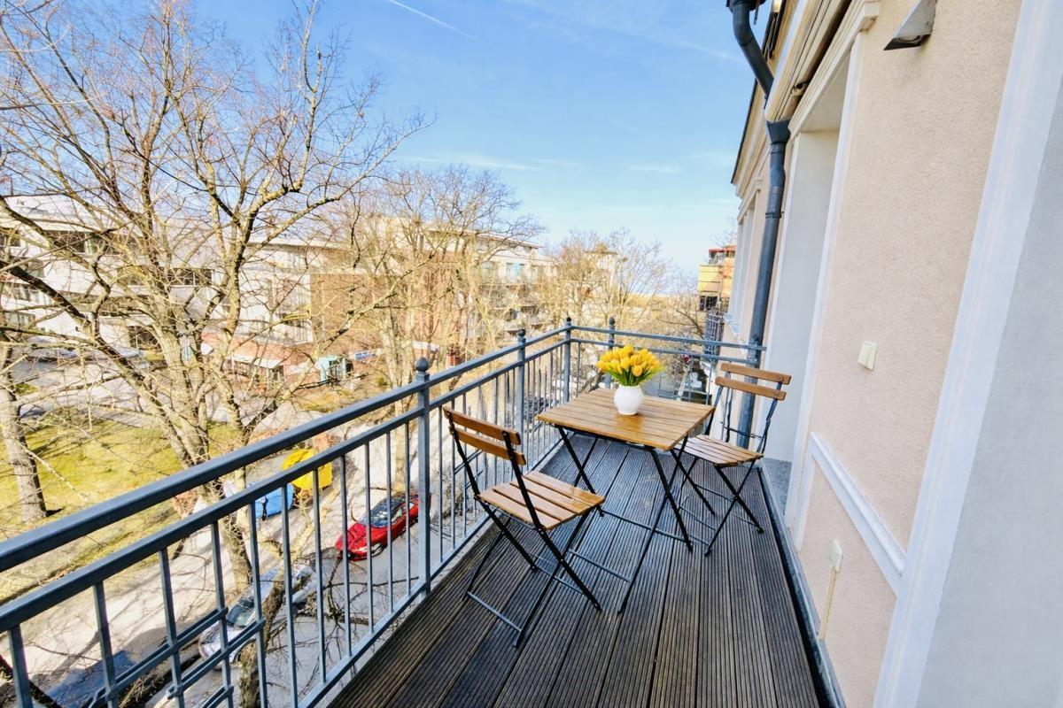 Balcony with wooden table and chairs, yellow flowers, and city view.