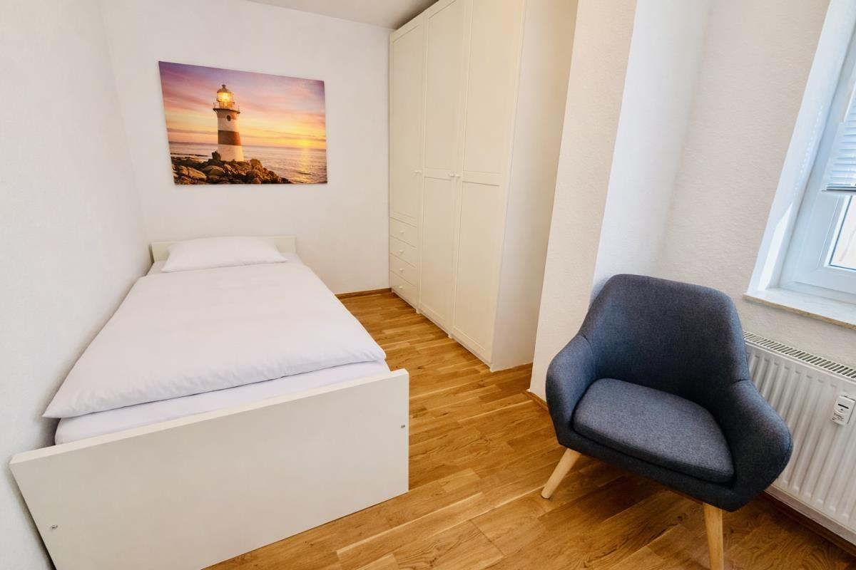 Ein Schlafzimmer mit Bett, Kleiderschrank und Sessel.