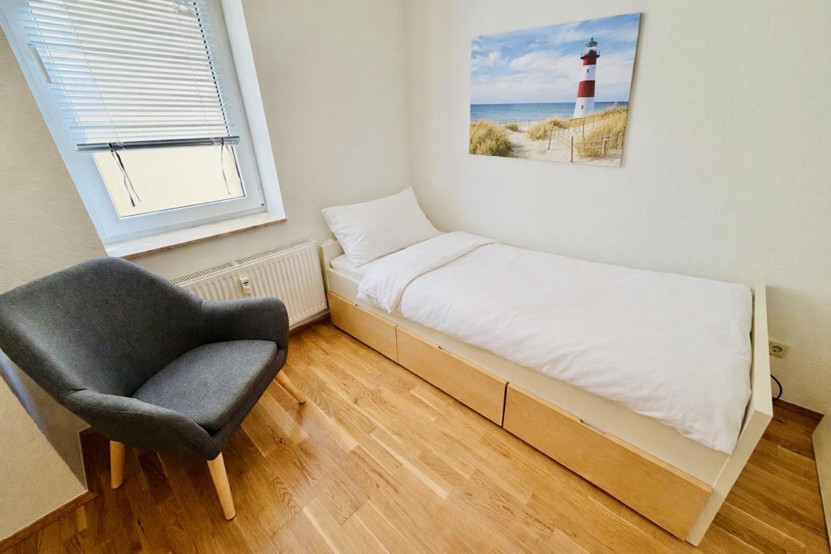 Ein Schlafzimmer mit einem Bett, einem Stuhl und einem Fenster.