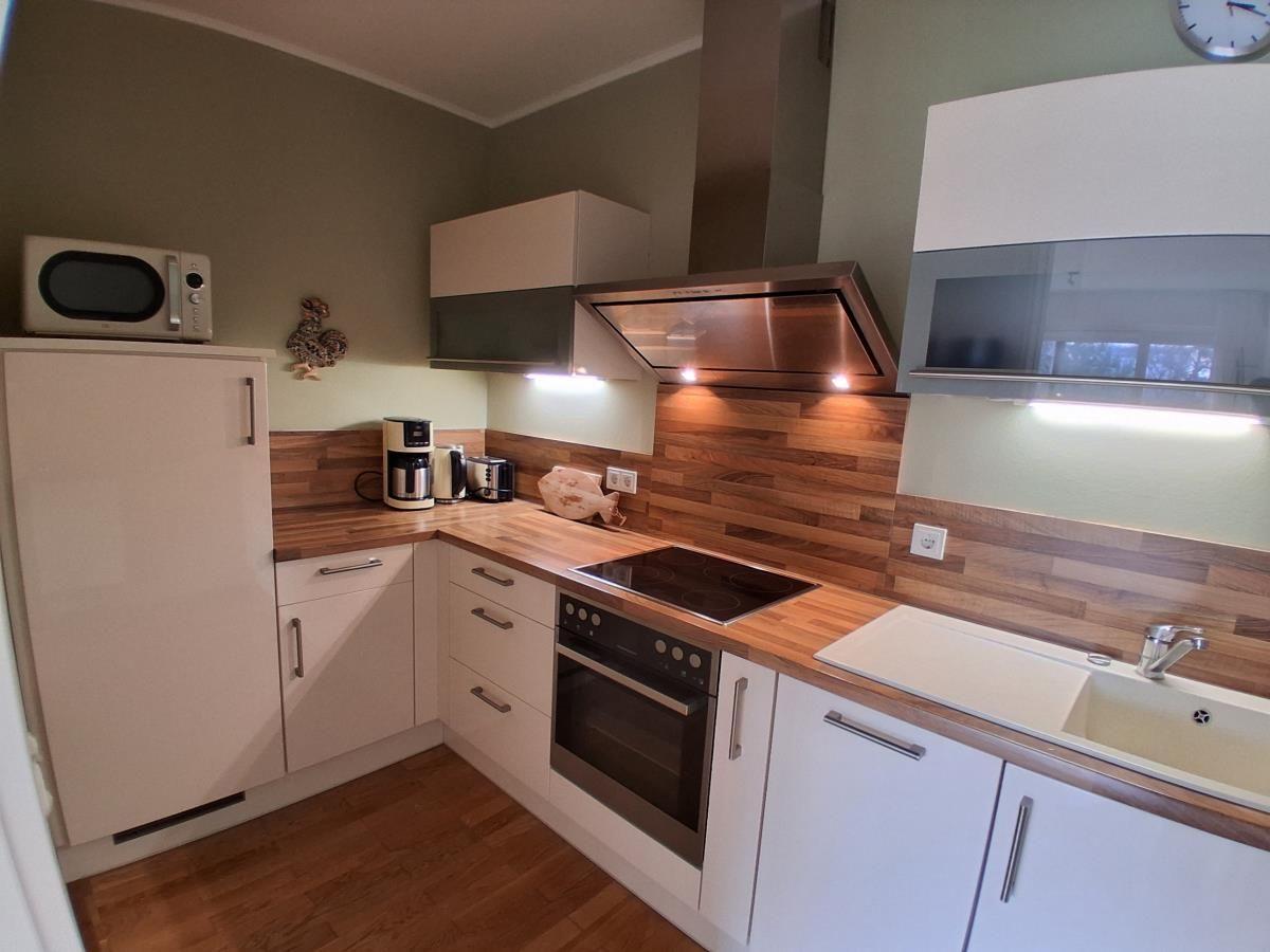Küche mit Holz Arbeitsplatte, Herd, Spüle und Kühlgerät.
