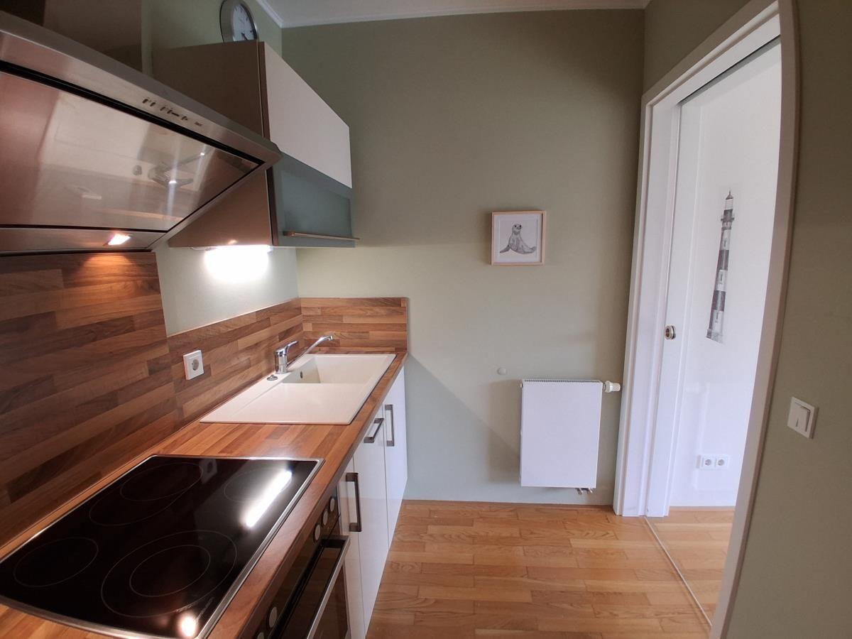 Küche mit Holz Arbeitsplatte, Spüle und Herd. Tür führt in angrenzenden Raum.