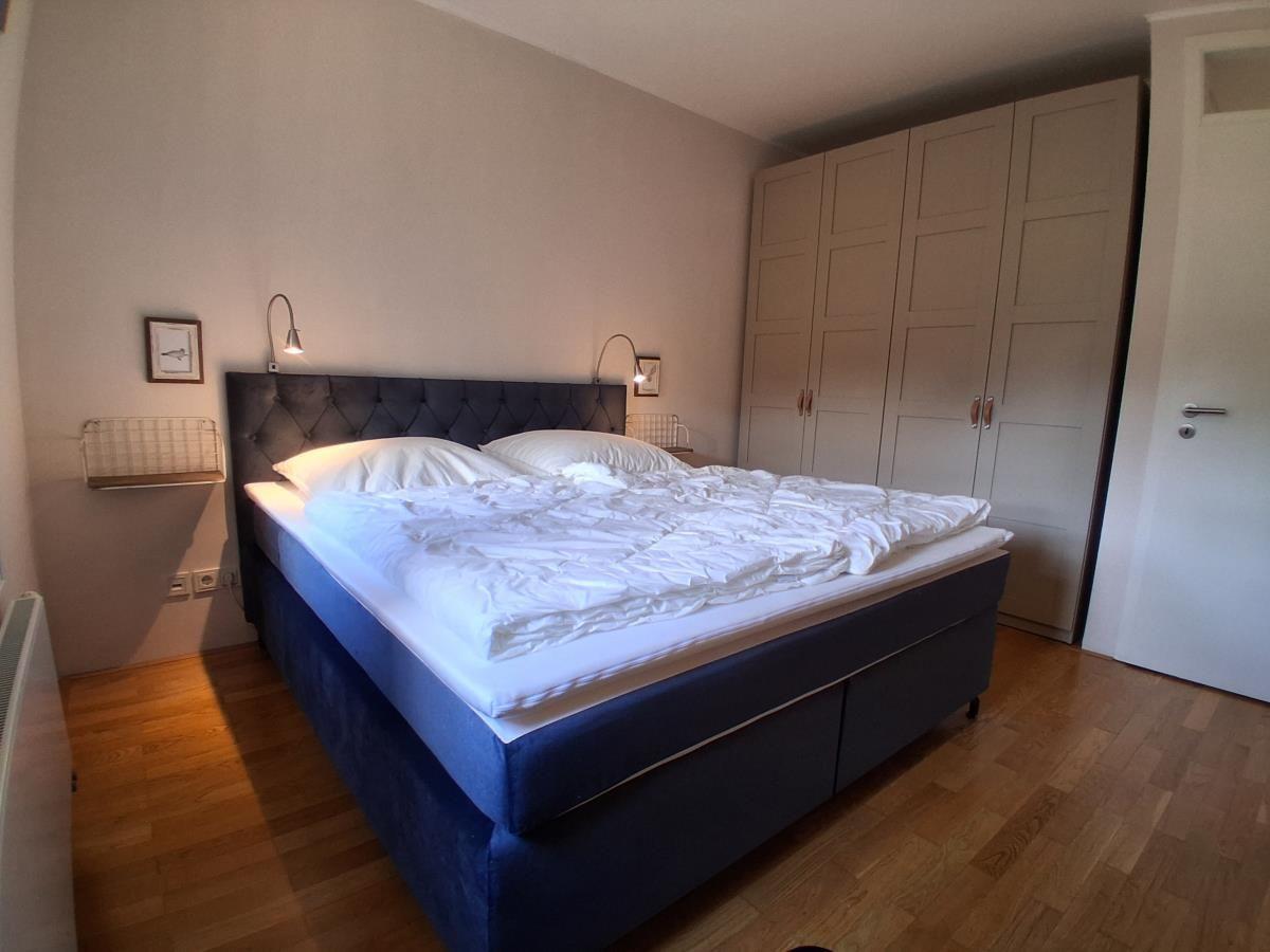 Schlafzimmer mit Bett, Kleiderschrank und Holzboden.