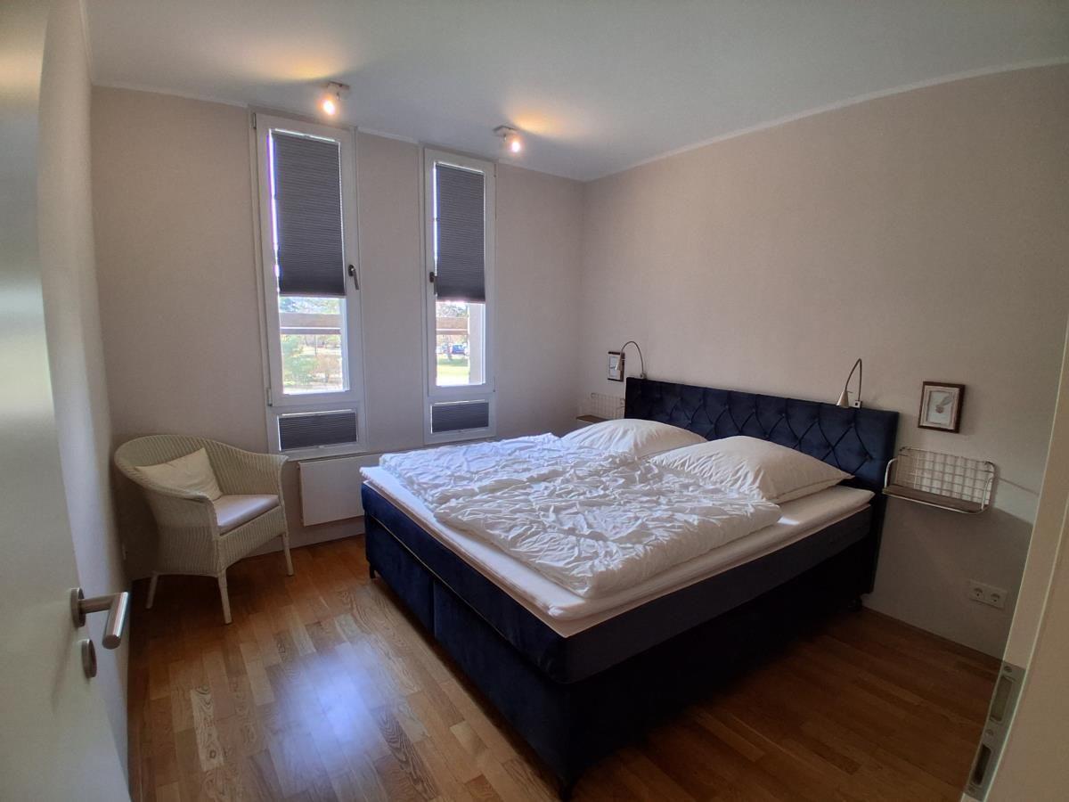 Schlafzimmer mit Bett, Stuhl und Fenstern
