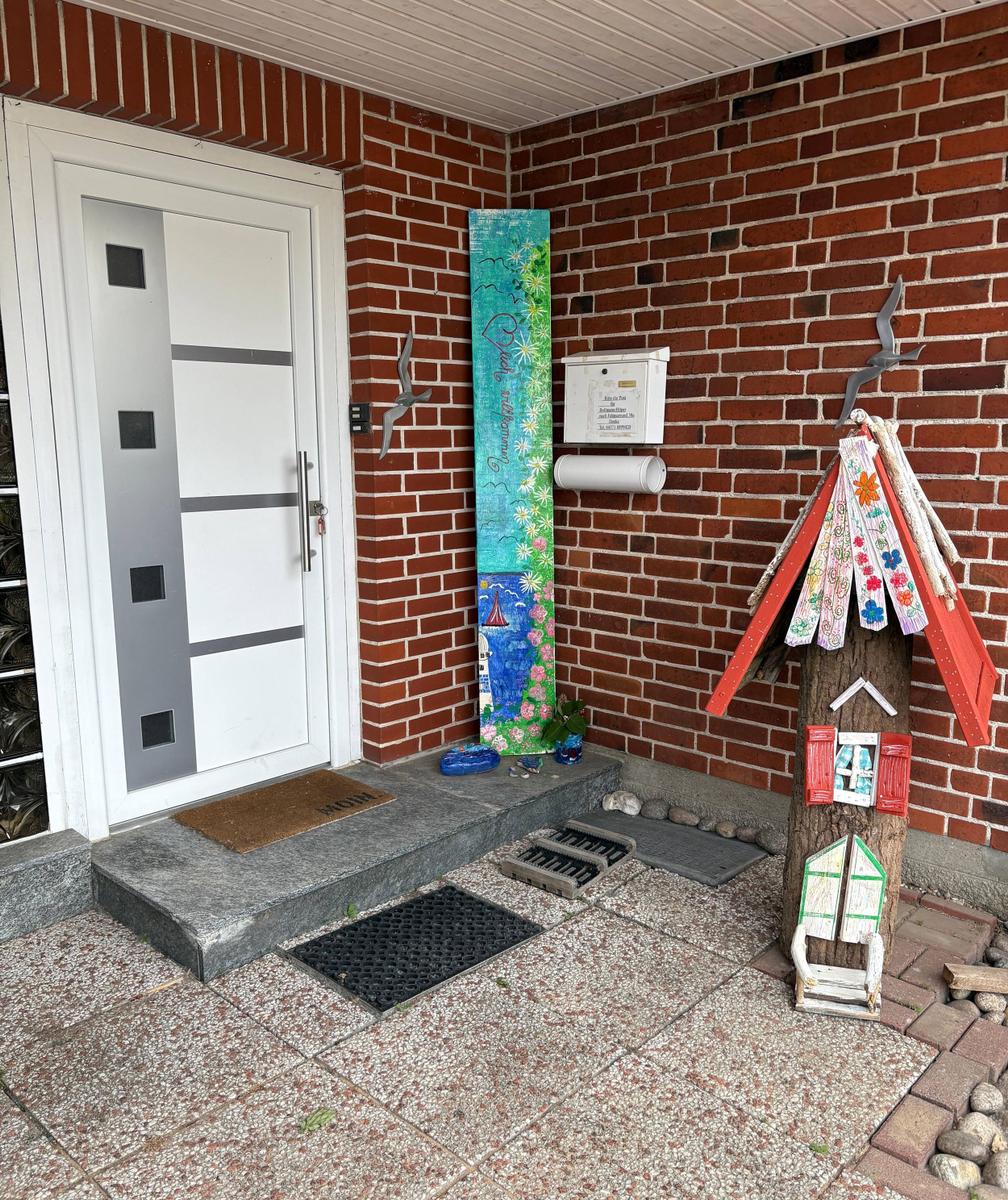 Eingang mit rotem Backsteinhaus, Briefkasten und buntem Holzhaus.