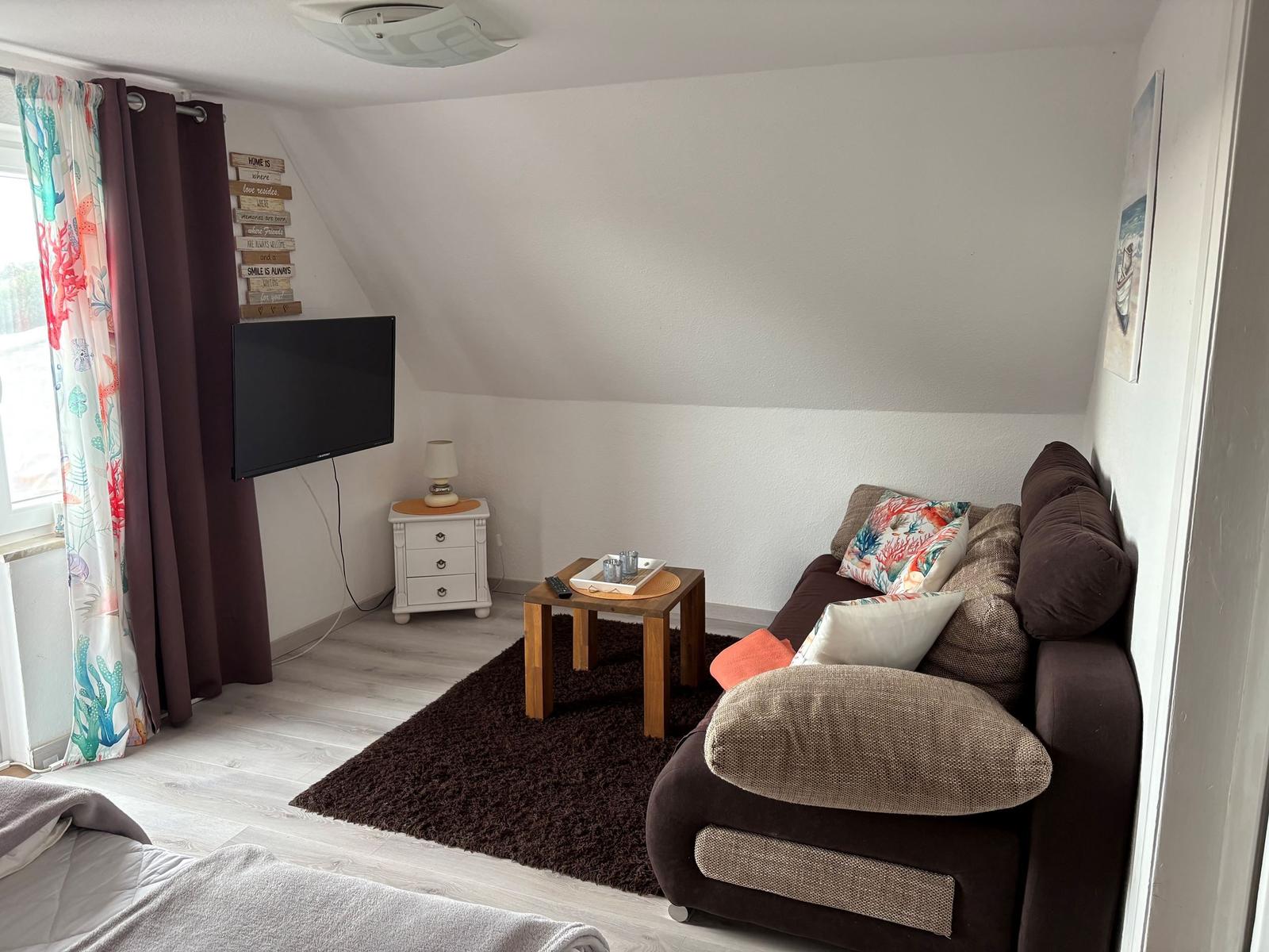 Wohnzimmer mit Sofa, Fernseher und Holztisch auf Teppich