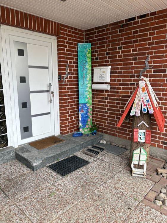 Eingang mit weißen Tür, rotem Ziegelwand und buntem Holzhaus.