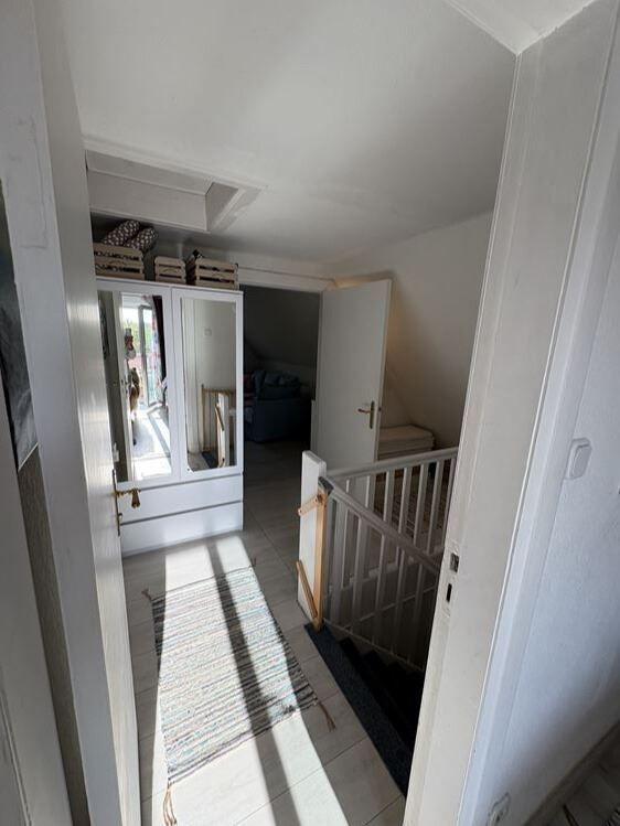 Hausflur mit Garderobe, Teppich und Treppenhaus zur oberen Etage.