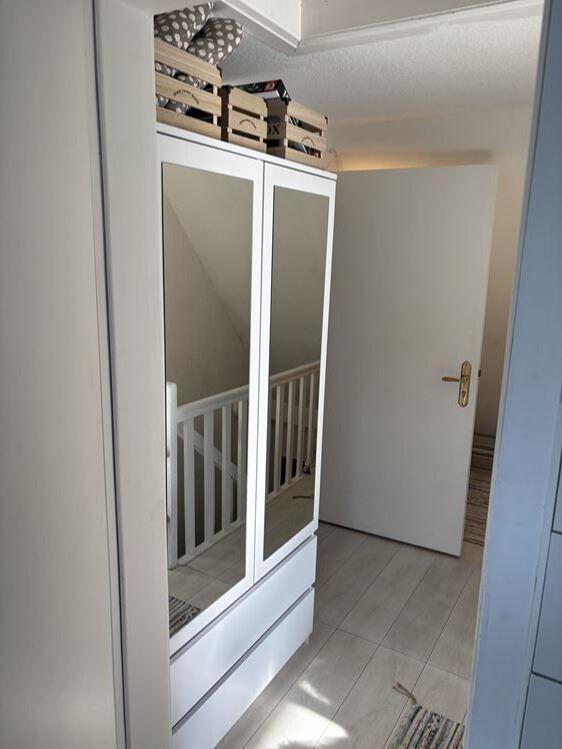 Schlafzimmer mit Spiegelschrank und Holzboxen oben