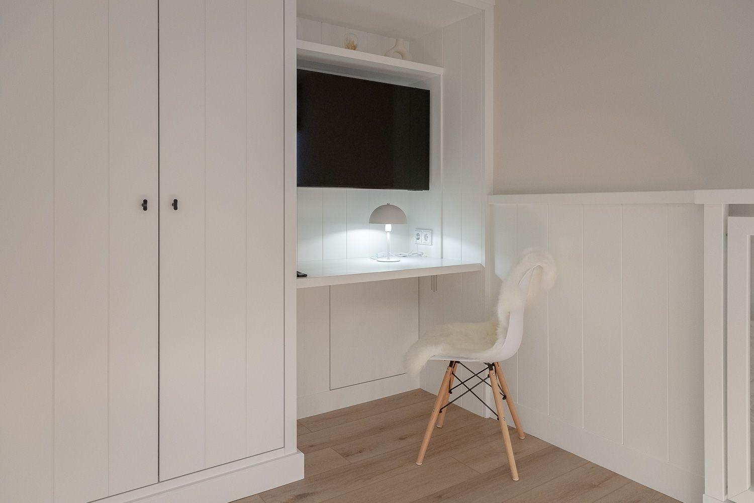 Schreibtisch mit TV und Schrankeinbauten.