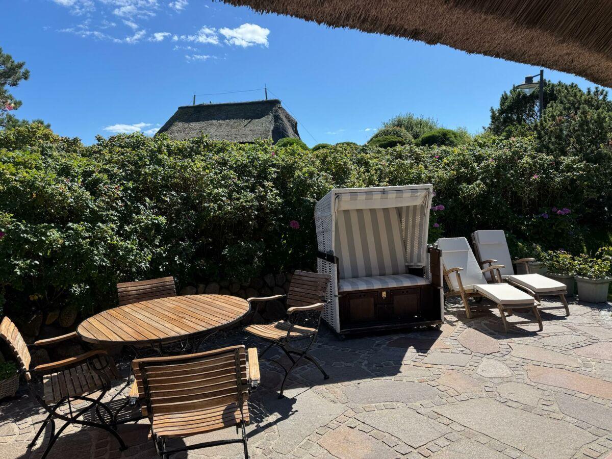 Eigener Garten mit Strandkorb und Liegen und Gartentisch und Stühle.