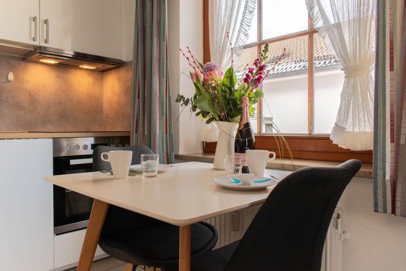 Essbereich mit Tisch, Stühlen und Blumen am Fenster