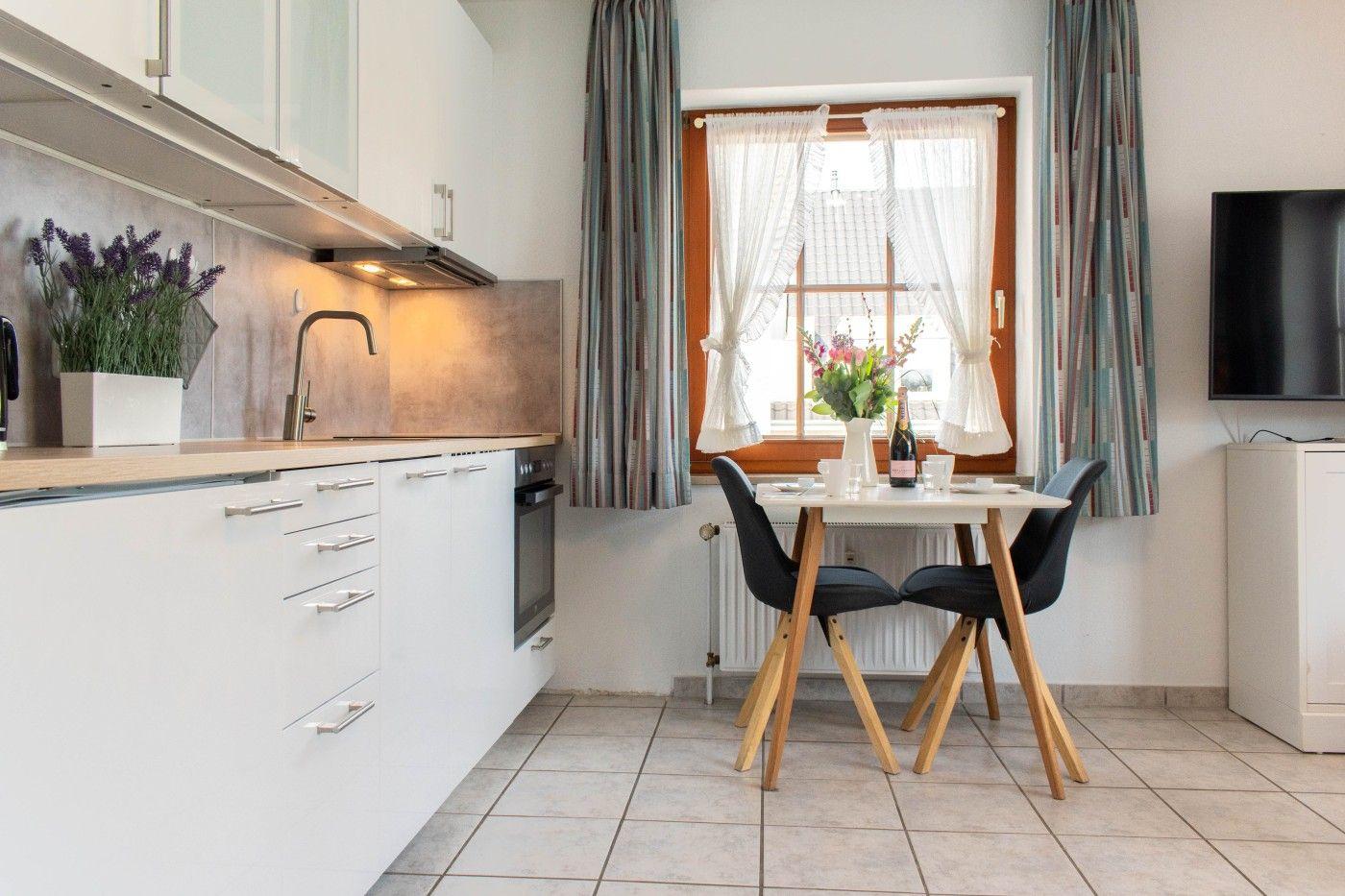 Küche mit Essbereich, Fenster mit Vorhängen und Fernseher.