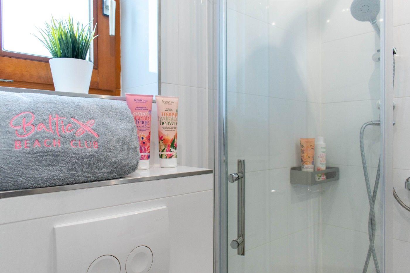Badezimmer mit Dusche, Handtüchern und Pflegeprodukten.