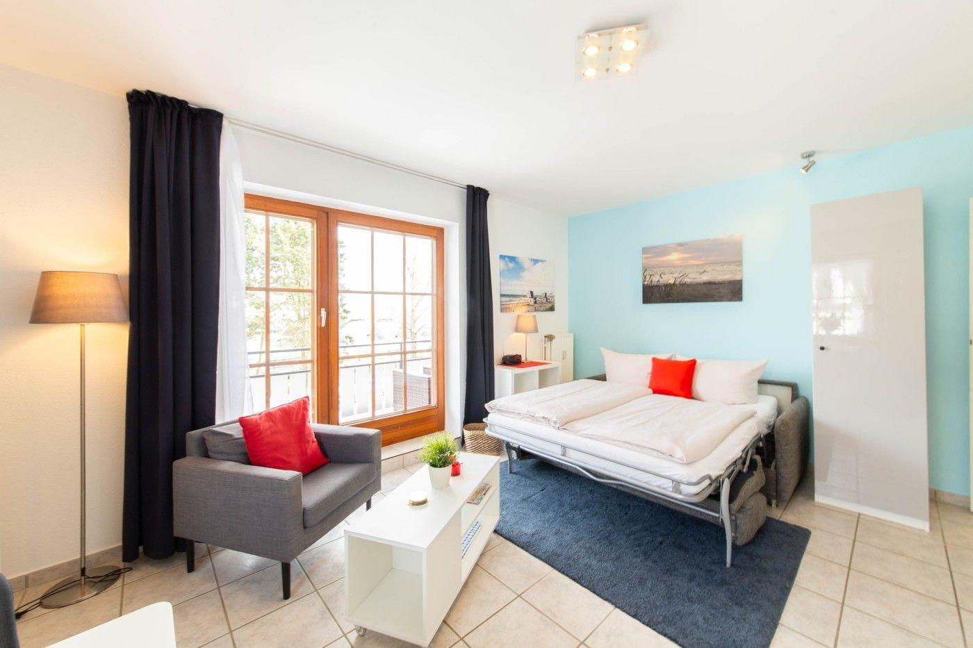 Zimmer mit Schlafplatz, Sitzgelegenheit und Fenster zur Terrasse.