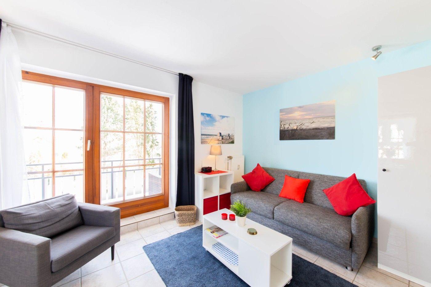 Wohnzimmer mit Sofa, Sessel und Fenster zur Terrasse.