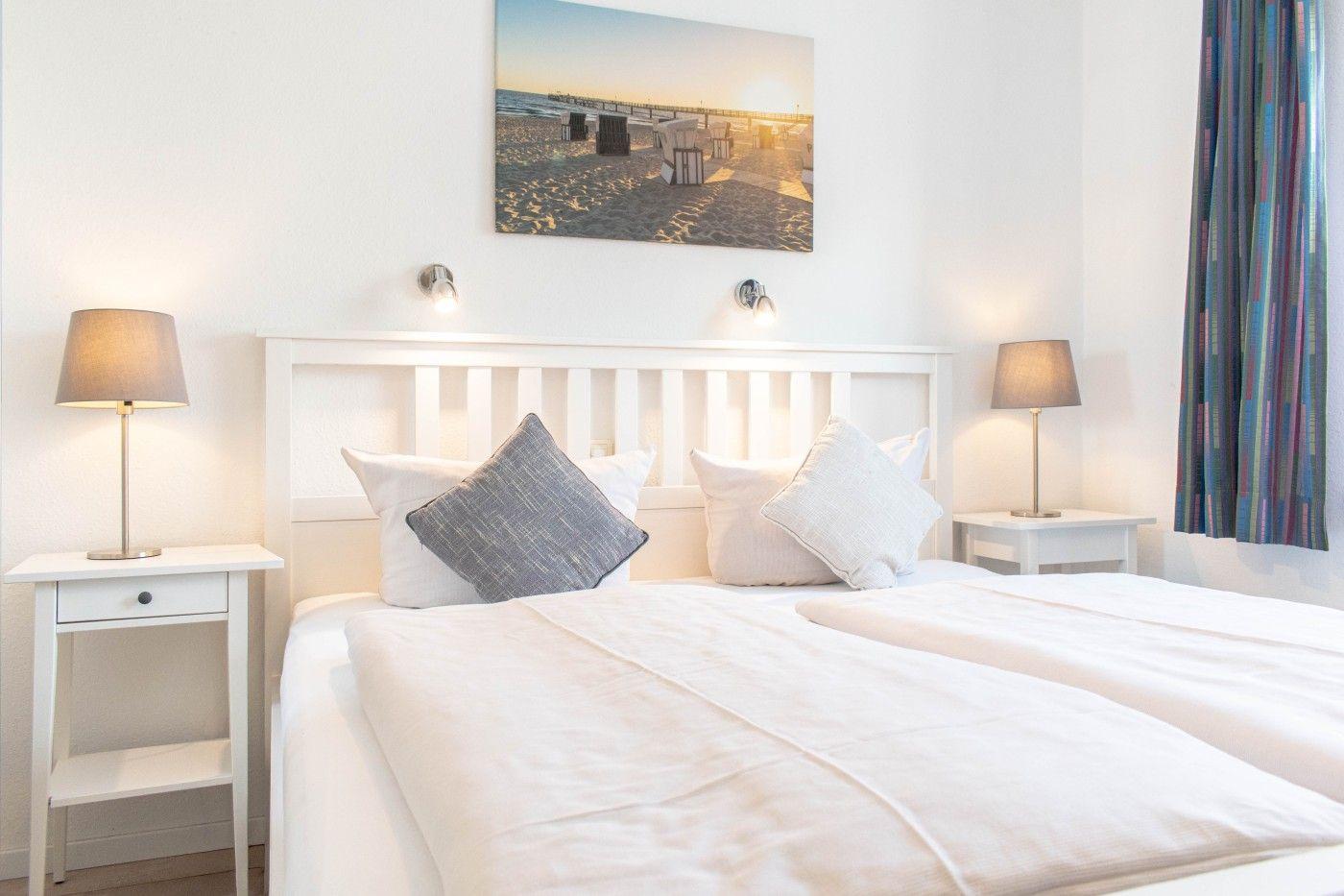 Schlafzimmer mit Bett, zwei Nachttischen und Wandbild.