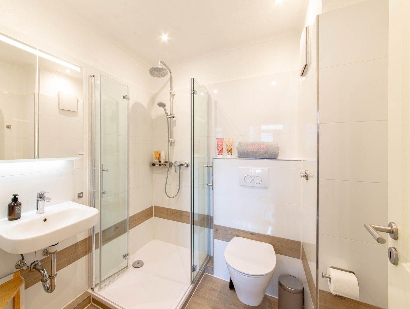 Badezimmer mit Dusche, Waschbecken und Toilette.