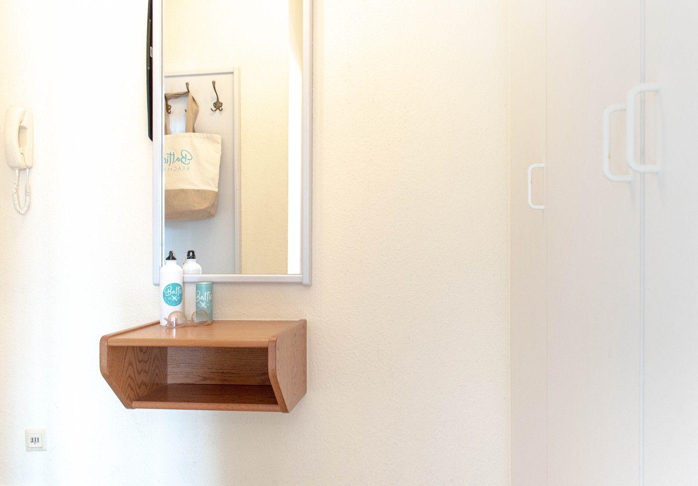 Spiegel mit Holzregal, Duschgut und Wandtelefon in einem Badezimmer.