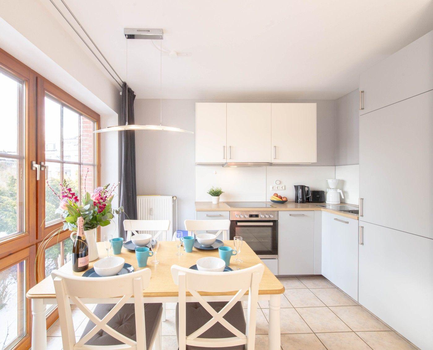 Küche mit Esstisch, Fenster und moderner Einbauküche.