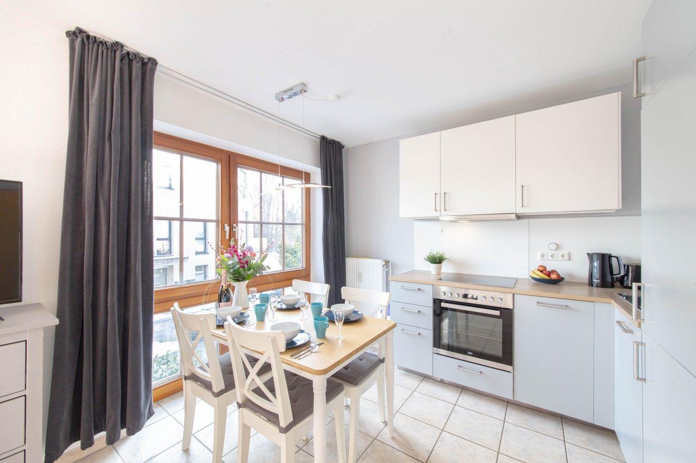 Küche mit Esstisch, Fenster und Küchenschränken.