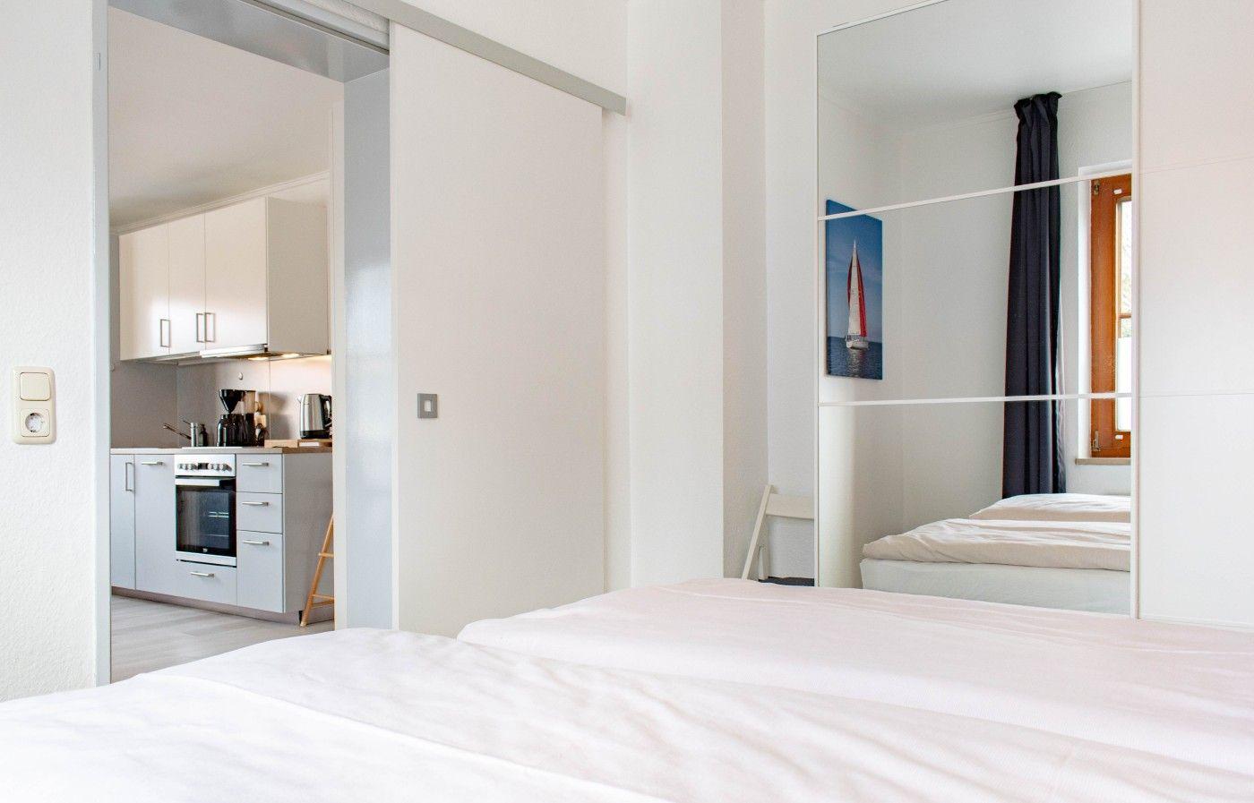 Schlafzimmer mit Blick in die Küche und Spiegelwand.