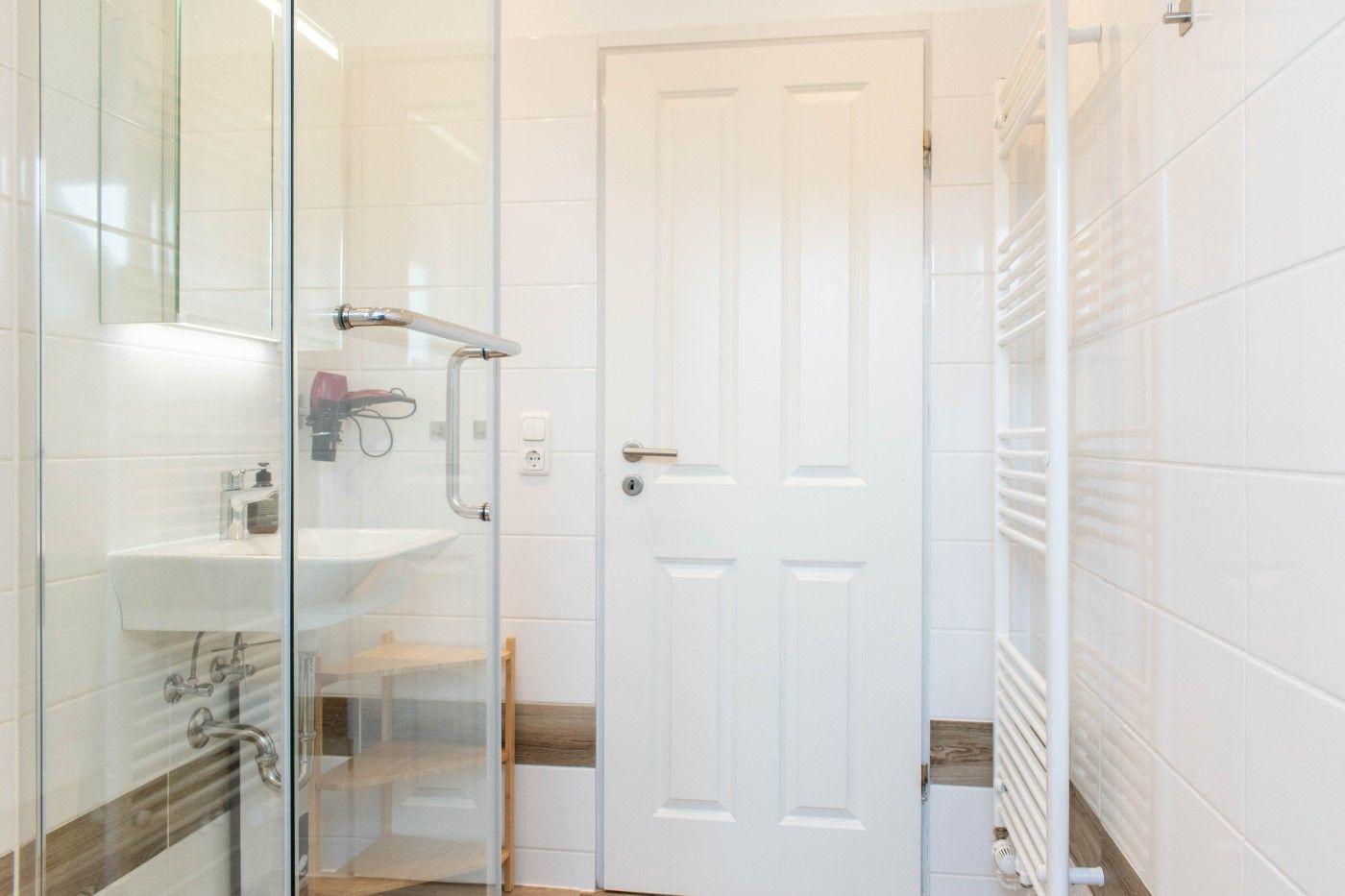 Badezimmer mit Dusche, Waschbecken und Heizung