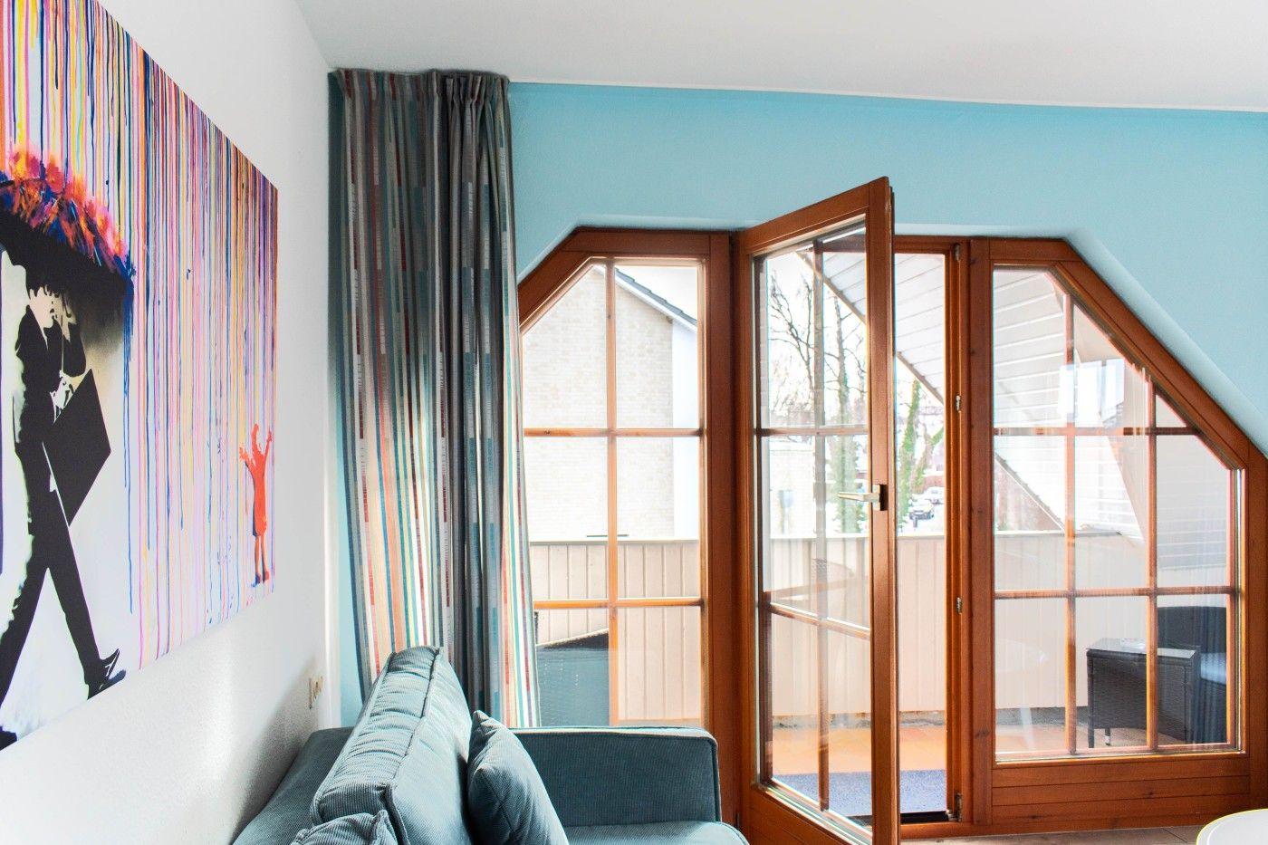 Wohnraum mit Sofa, Fenster und Wandbild