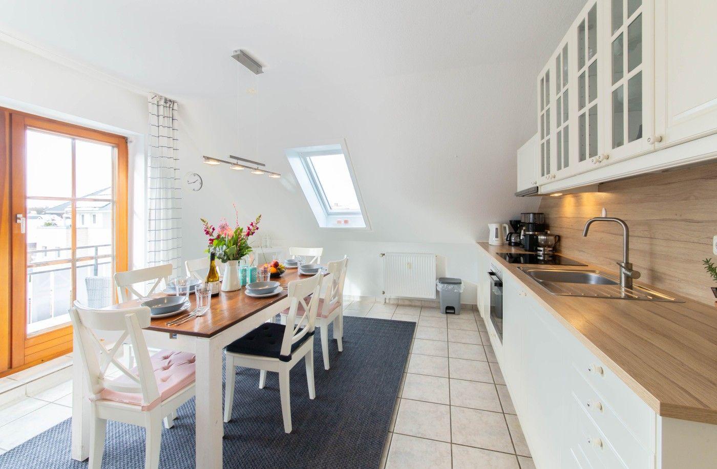 Küche und Essbereich mit Tisch, Stühlen und Fenster zur Terrasse.