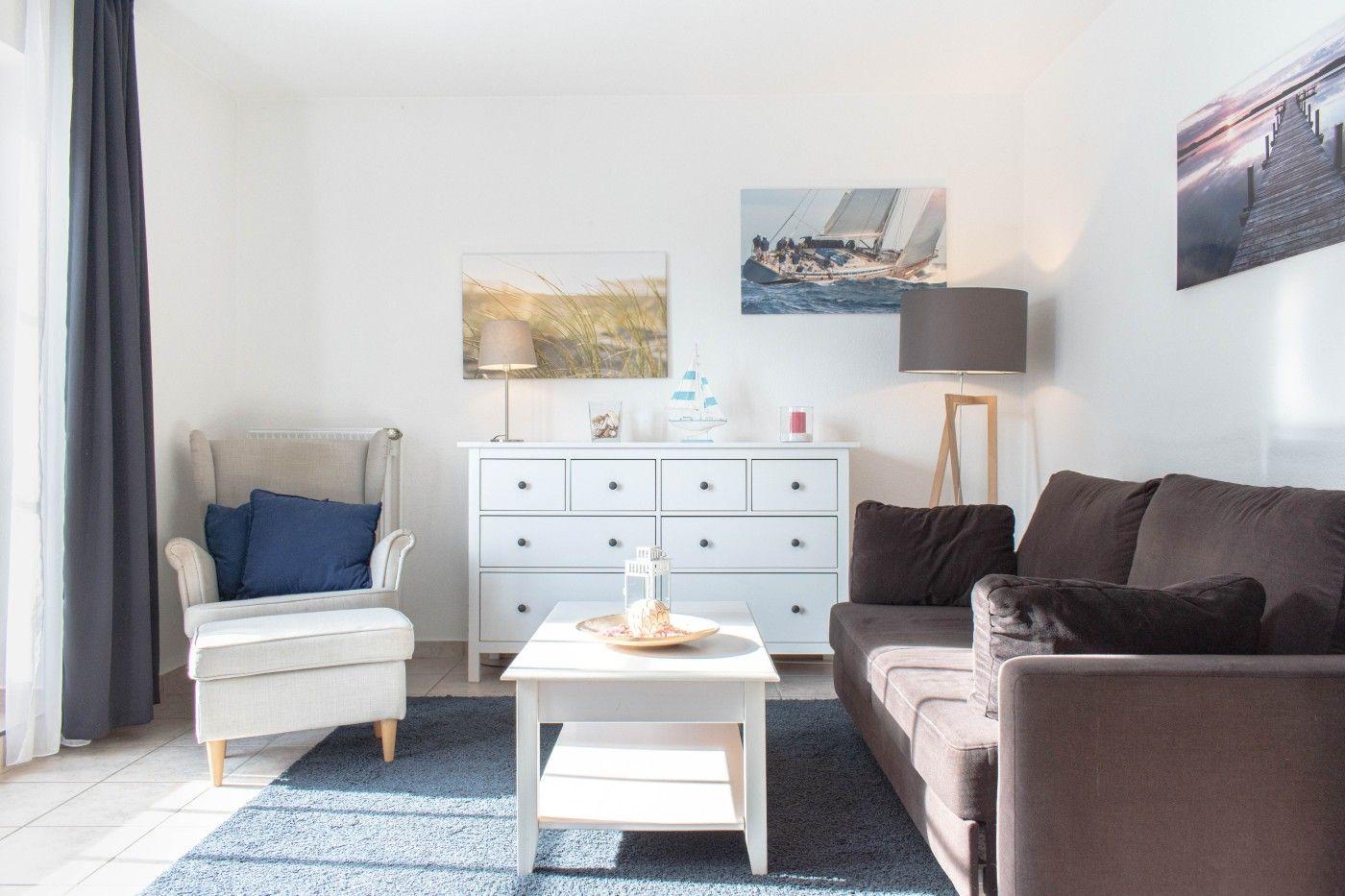 Wohnzimmer mit Sofa, Sessel, Tisch und Wandbildern.