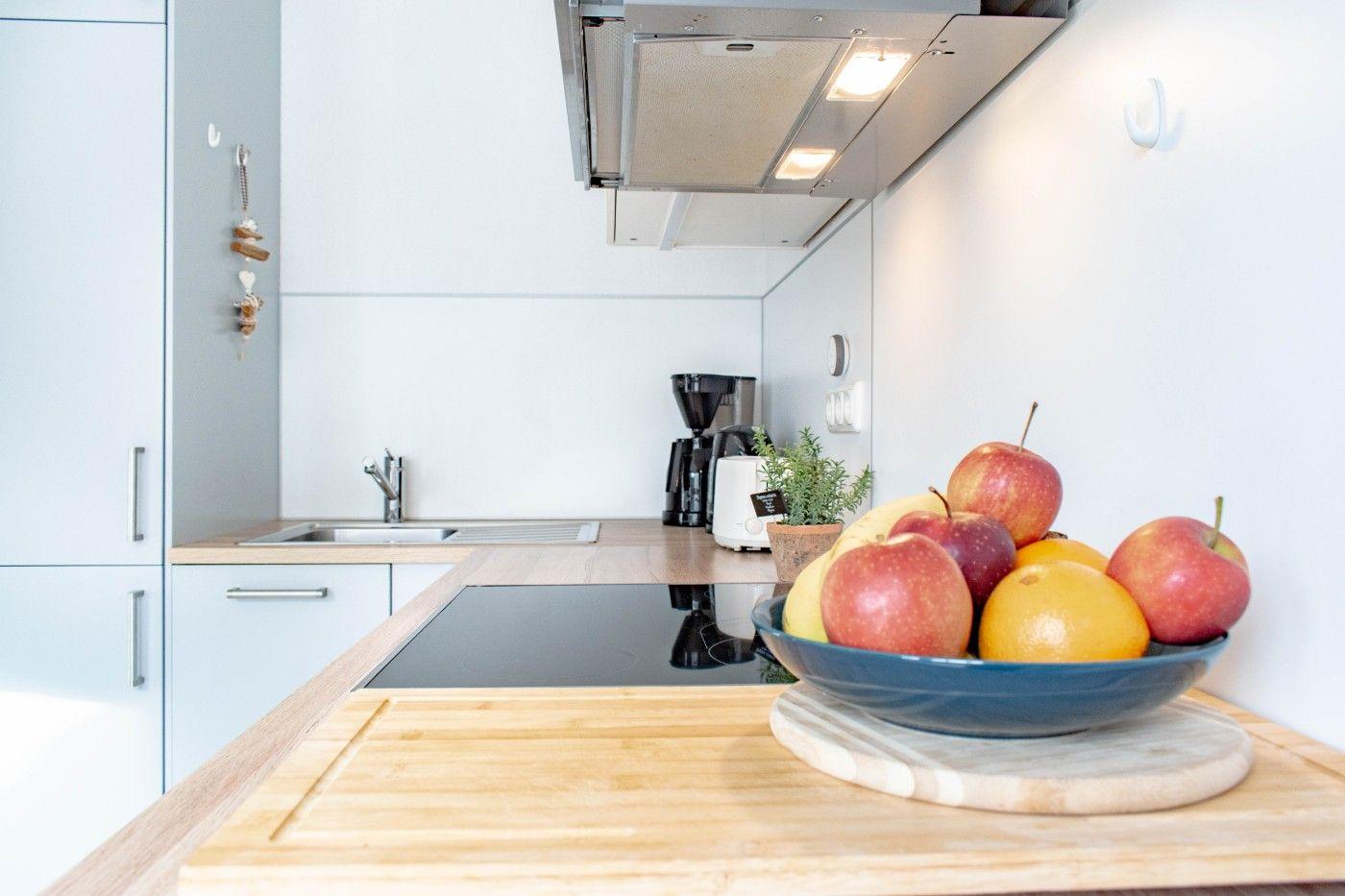 Küche mit Kochfeld, Spüle und Obstschale auf Arbeitsplatte.