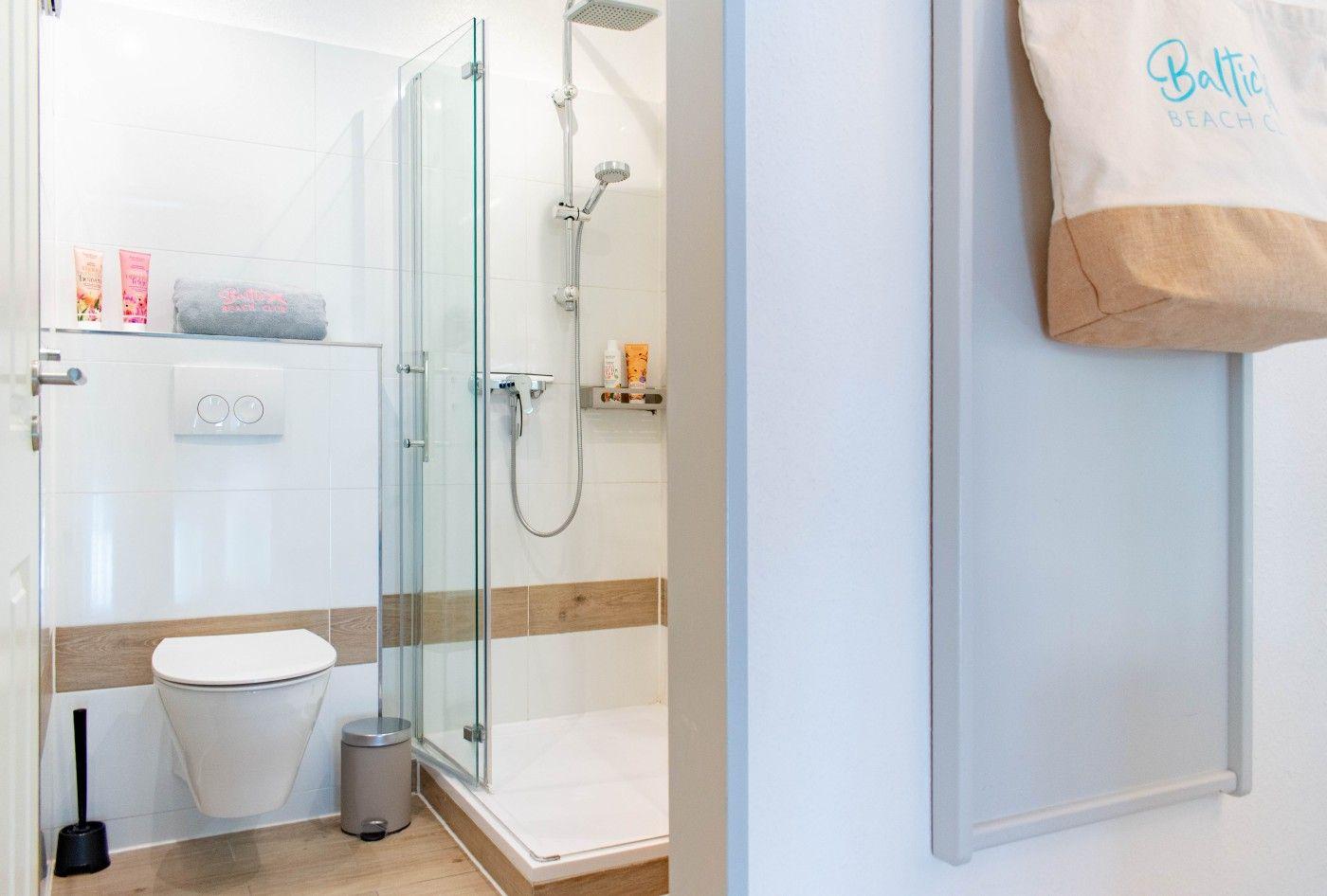 Badezimmer mit Dusche, Toilette und Badetuchhalter.