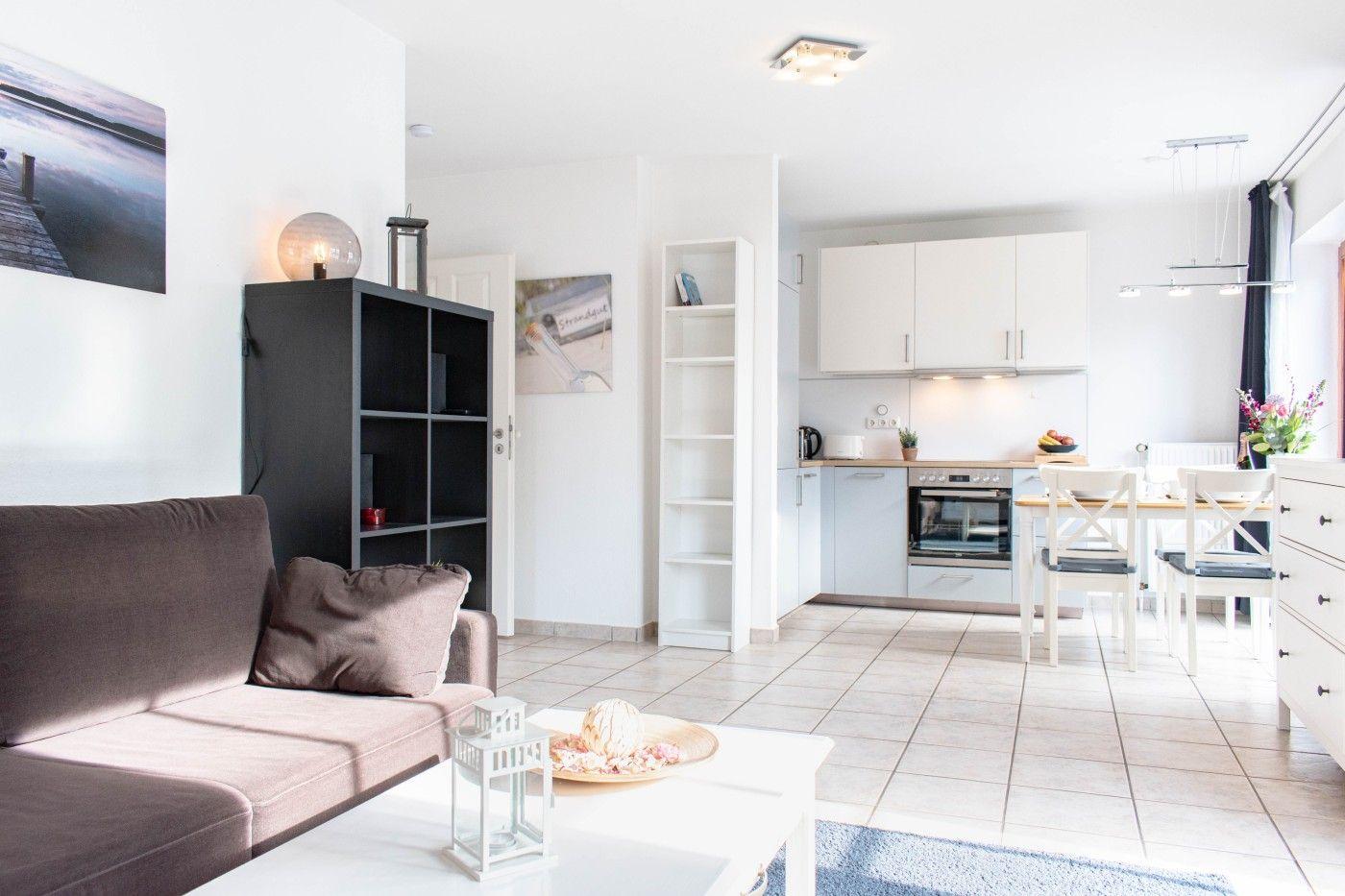 Wohn- und Essbereich mit Küche. Sofa, Tisch, Stühle und Küchenzeile sichtbar.