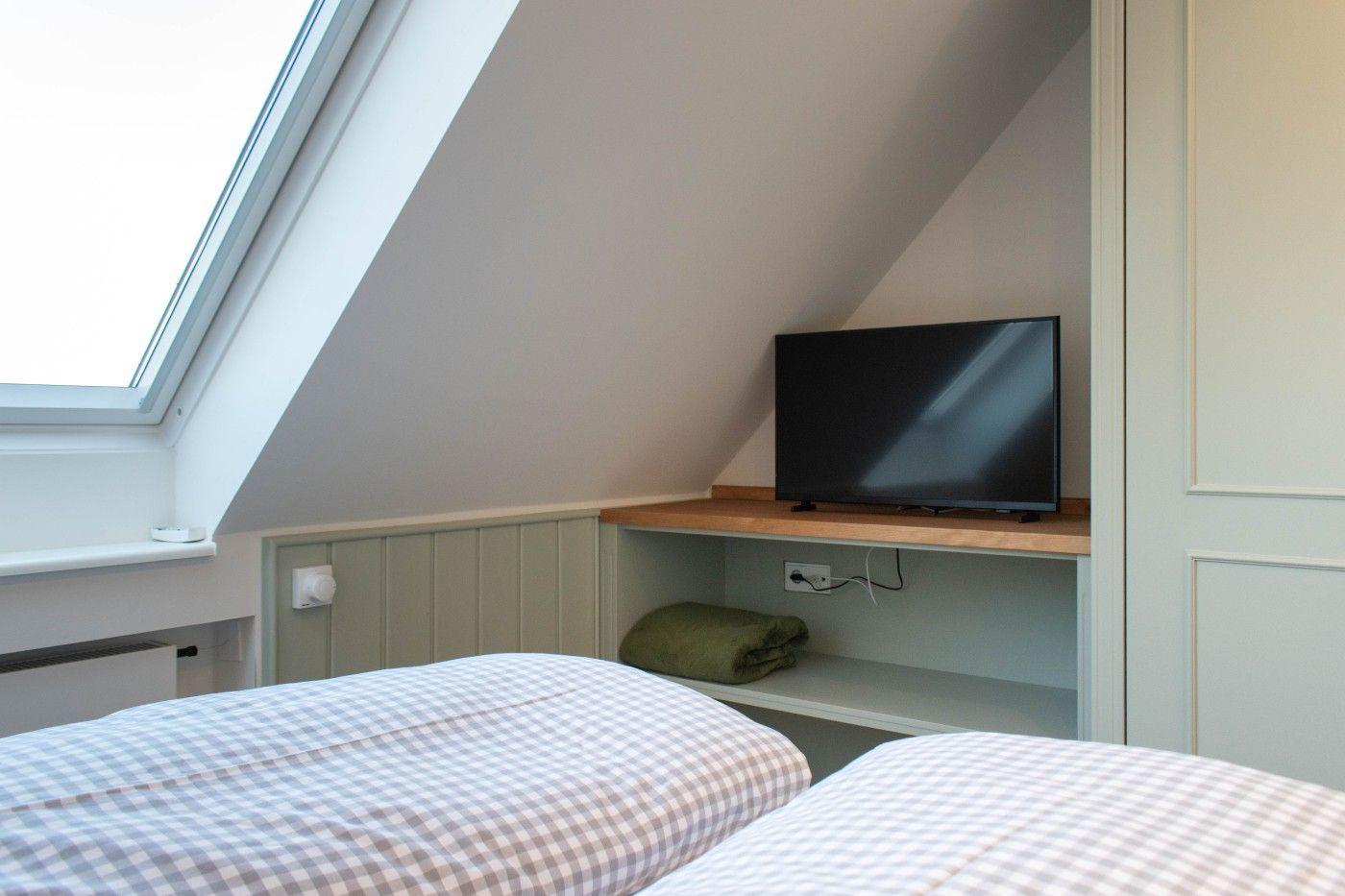 Schlafzimmer mit Dachfenster, TV und Bett