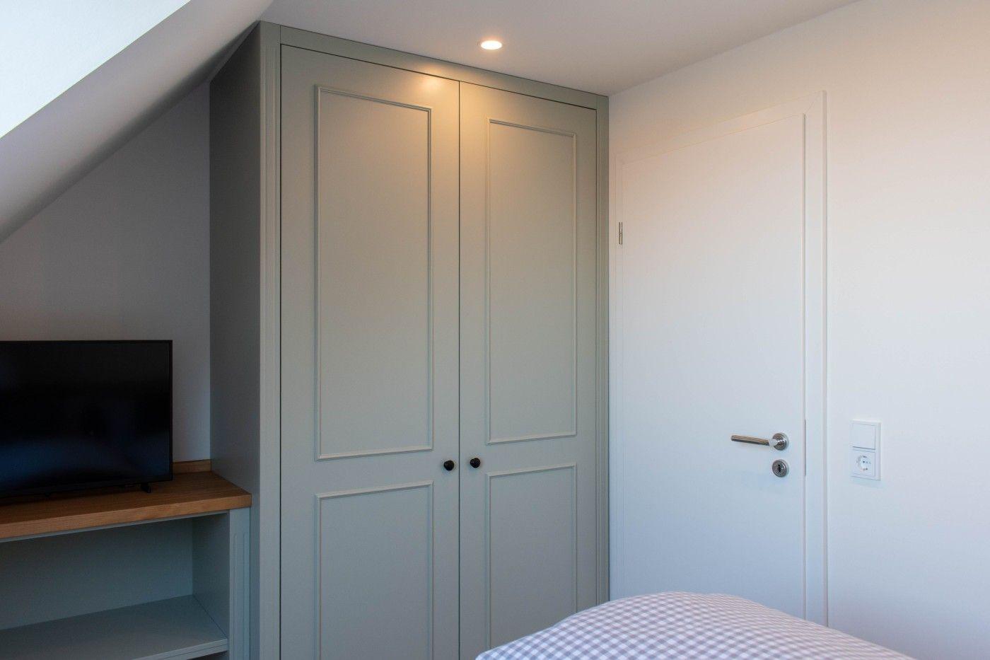 Schlafzimmer mit Kleiderschrank, Fernseher und Bett unter Dachschrägen.