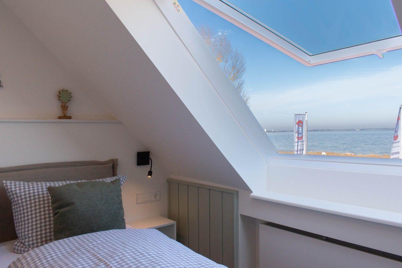 Schlafzimmer mit Dachfenster und Blick aufs Wasser.