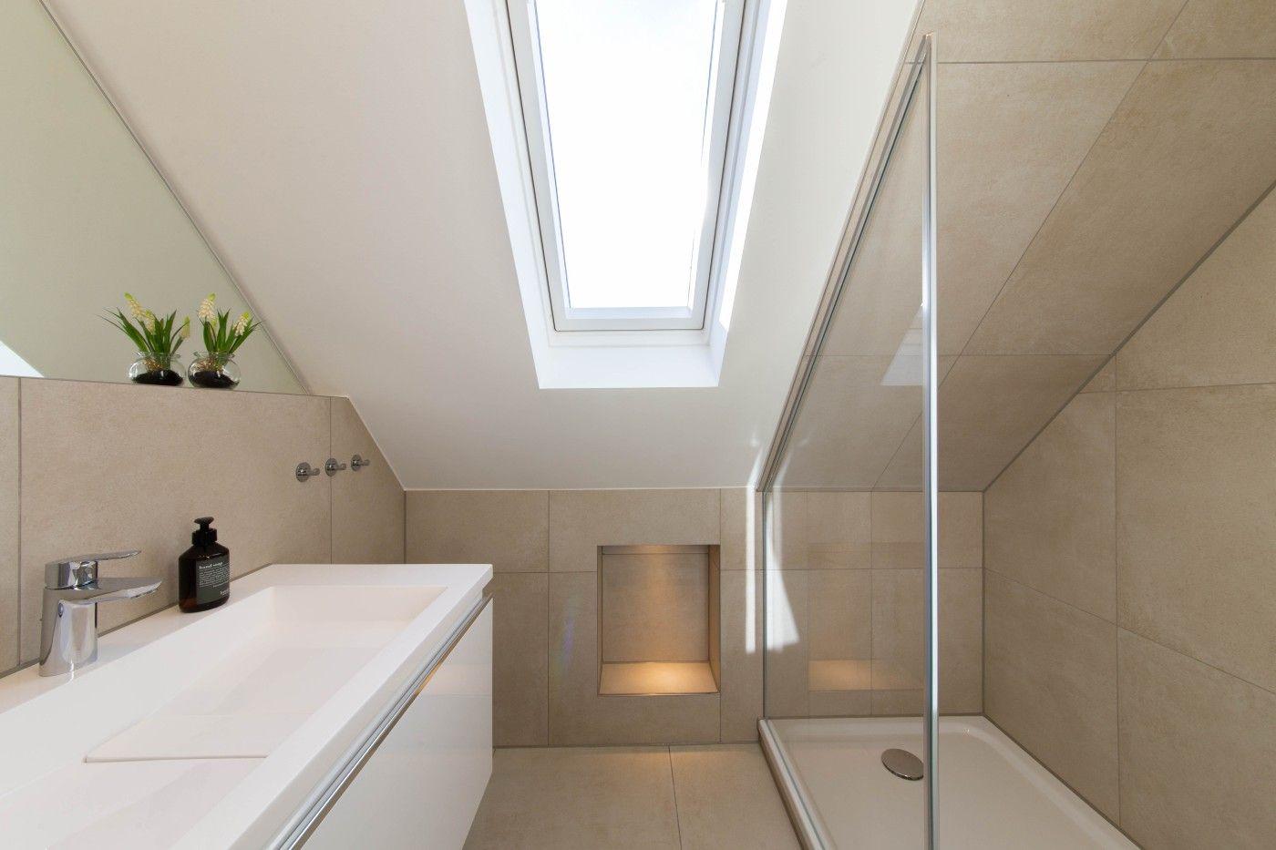 Badezimmer mit Dusche, Waschtisch und Dachfenster.