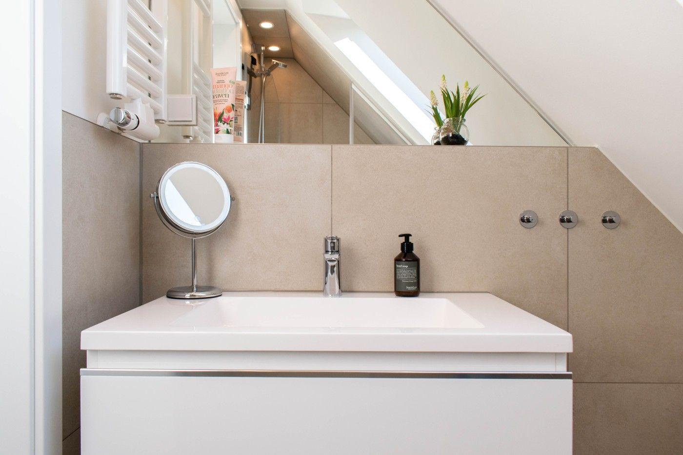 Badezimmer mit Waschtisch, Spiegel und Dusche unter Dachschräge.