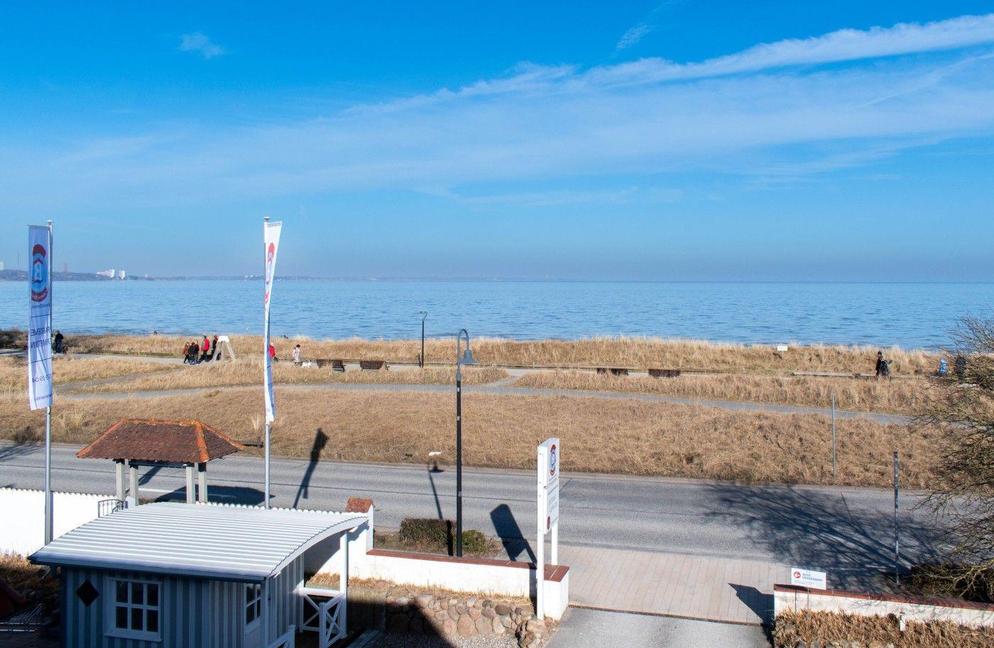 Meerfront mit Weg, Strand und kleinem Gebäude im Vordergrund.