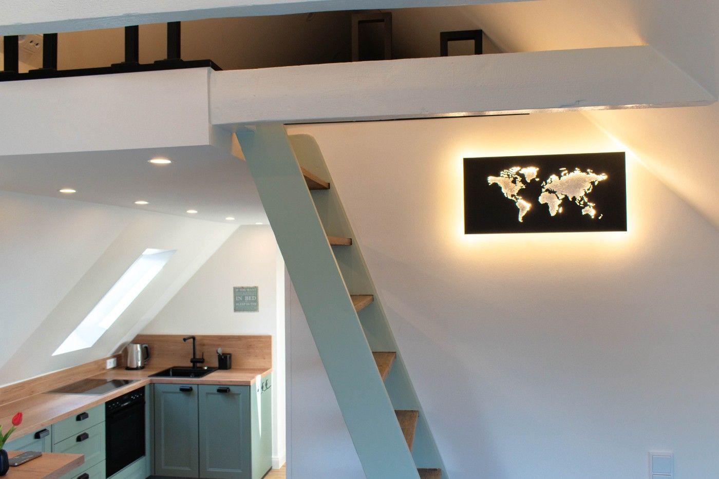 Küche mit Holzoberfläche und Stufen zur Galerie. Weltkarte an der Wand.
