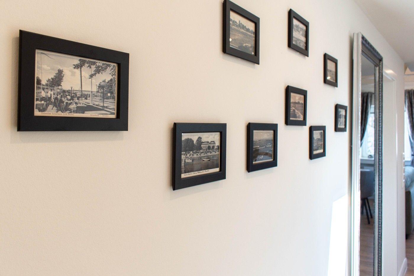 Wand mit mehreren gerahmten Schwarz-Weiß-Fotografien und einem Spiegel im Flur.