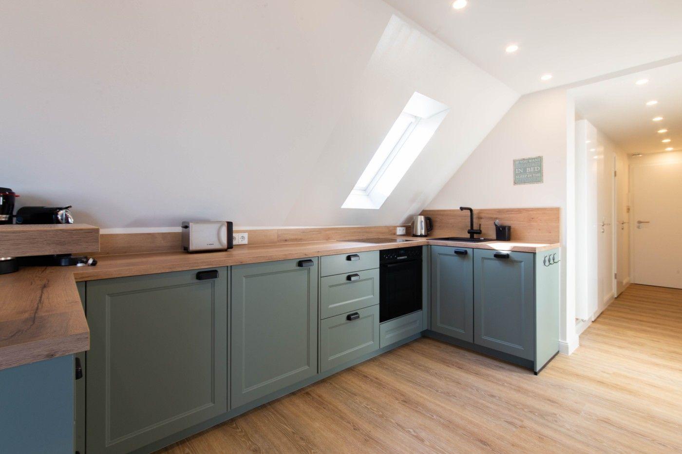 Küche mit grünen Schränken, Holz Arbeitsplatte und Dachfenster.