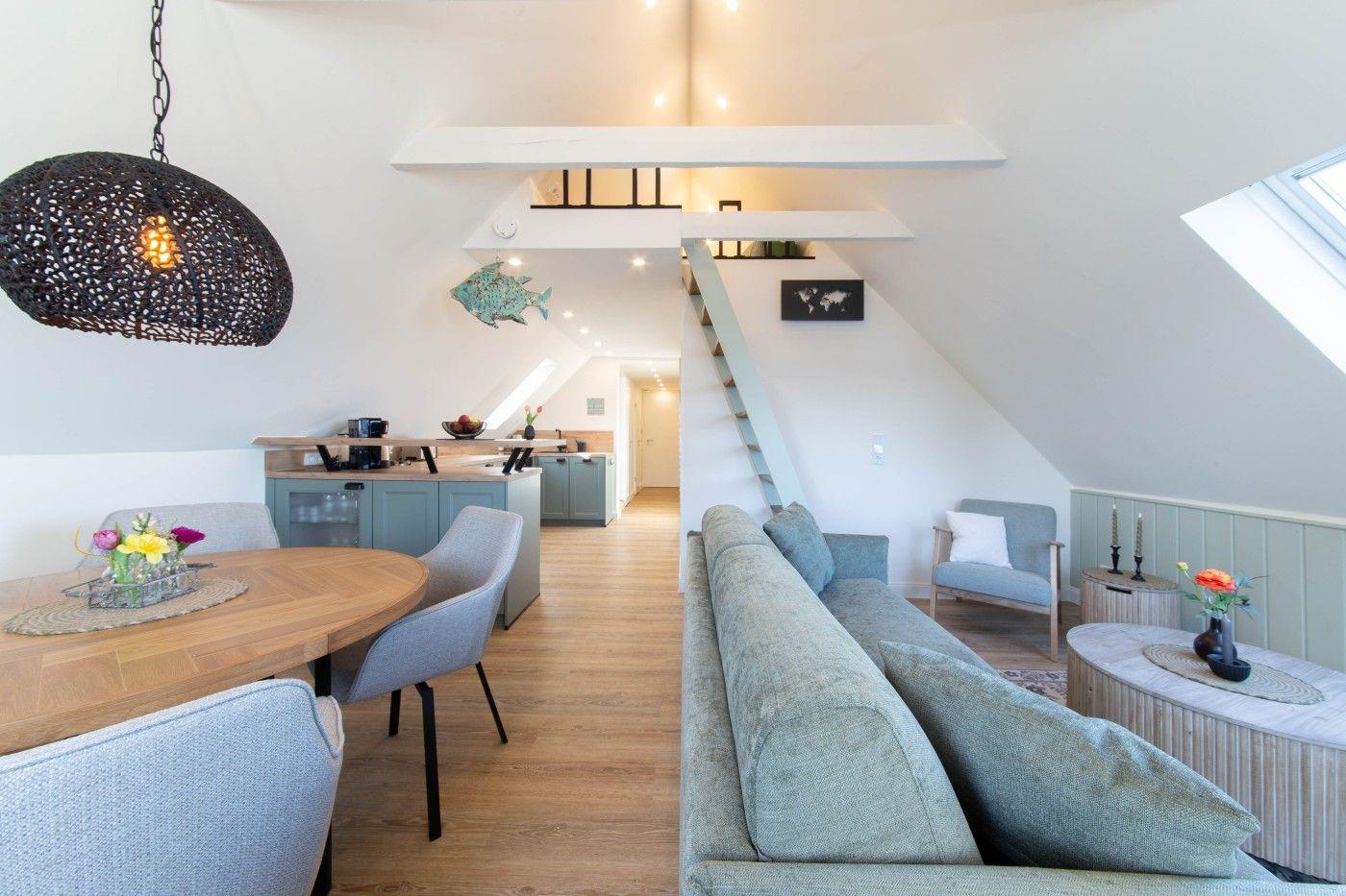 Wohnung mit Essbereich, Sofa und Treppe zur oberen Etage.