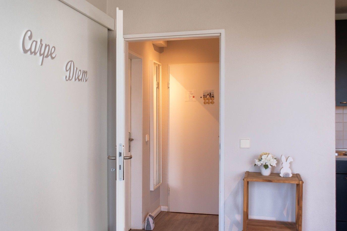 Eingangsbereich mit Tür und kleinem Tisch mit Blumen und Hase.