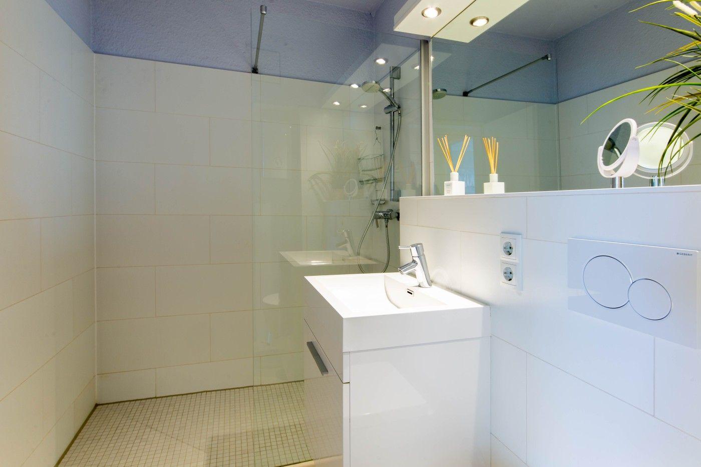 Badezimmer mit Dusche, Waschbecken und Spiegel.