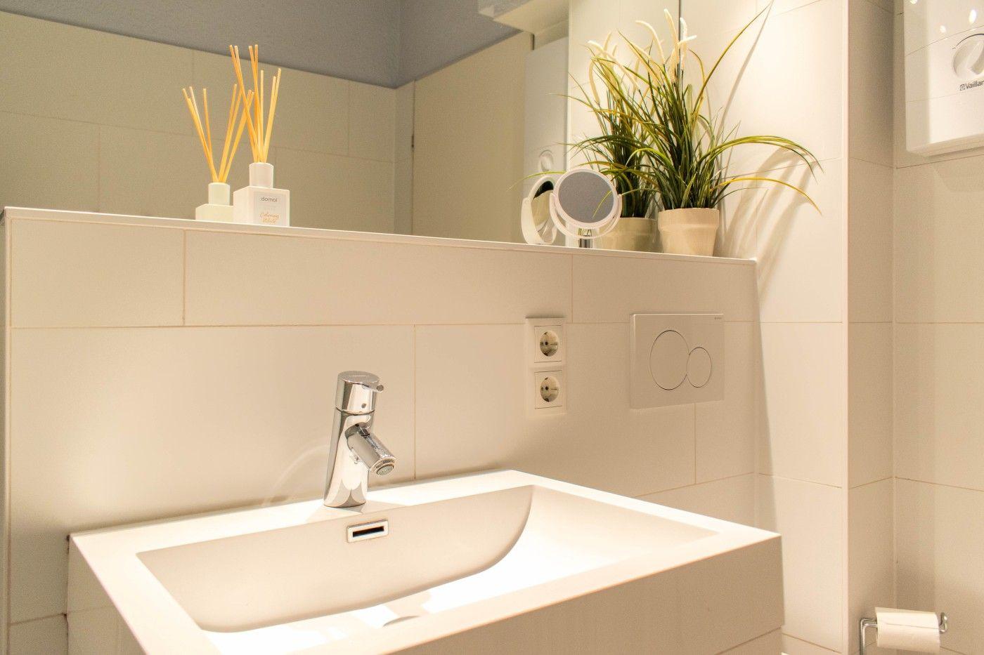 Waschbecken mit Spiegel, Pflanze und Aromalampen