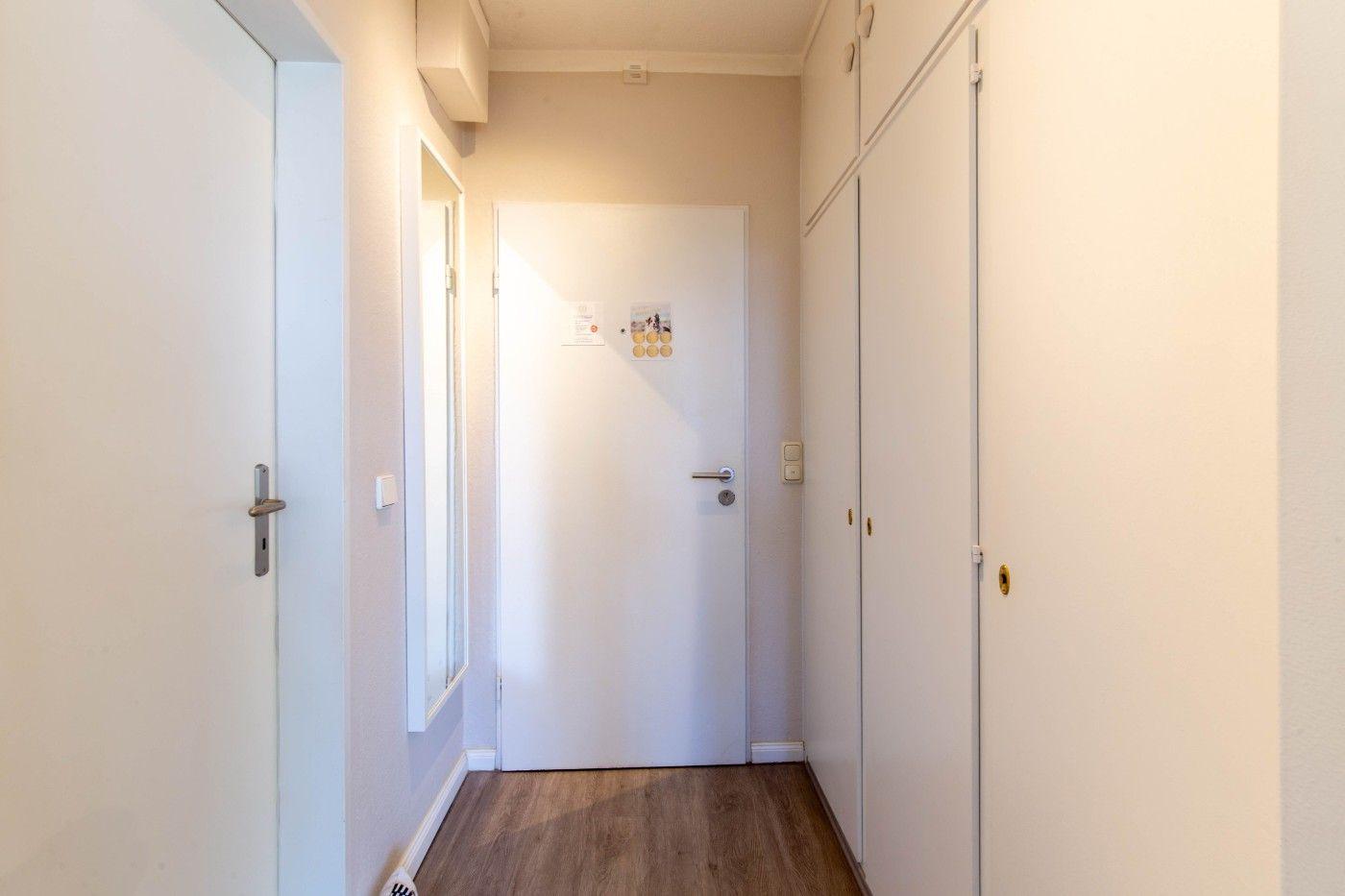 Flur mit Holzboden, weißen Türen und Schränken an der Wand.