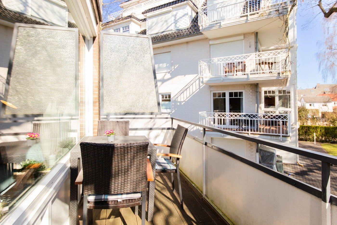 Terrasse mit Tisch und Stühlen, Sicht auf Wohnhaus mit Balkonen.